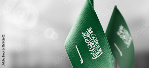 Small national flags of the Saudi Arabia on a light blurry background