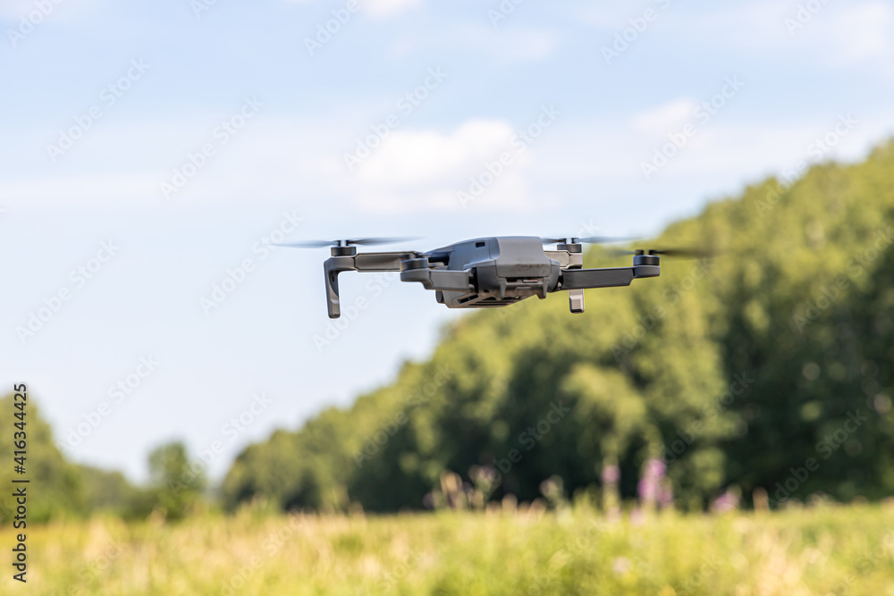 White unmanned aerial vehicle with four propellers and blades is outside on the blue sky background White unmanned aerial vehicle with four propellers and blades is outside on the blue sky background