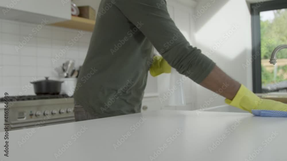 Man Cleaning Kitchen Work Surface with Rubber Gloves and Disinfectant Spray Man Cleaning Kitchen Work Surface with Rubber Gloves and Disinfectant Spray