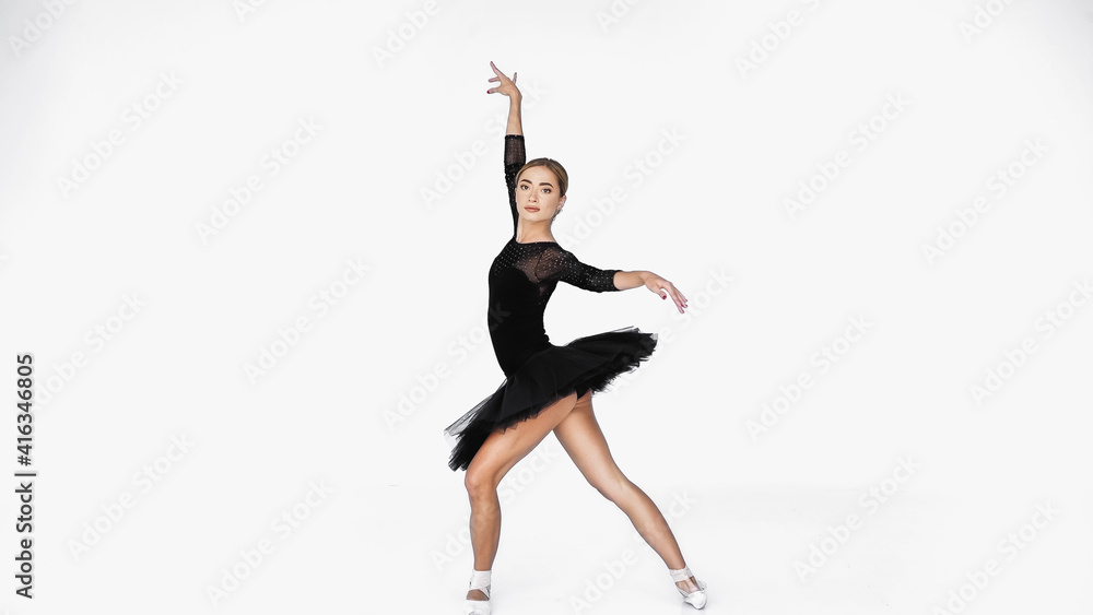 elegant ballerina in tutu skirt and pointe shoes dancing on white background