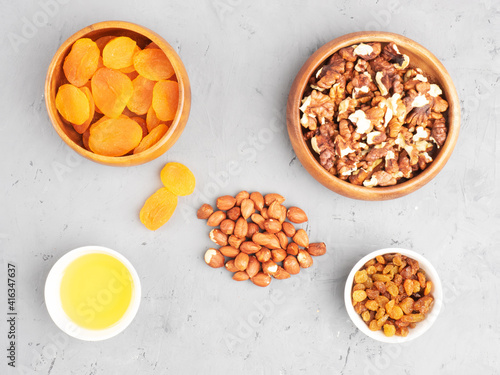 Dried apricots, nuts, raisins, honey on concrete background