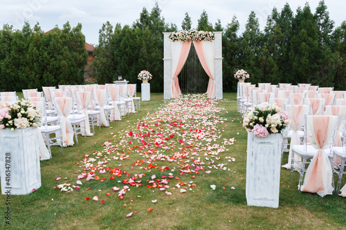Place for wedding ceremony in white color .White square wedding arch with bouquets of pastel roses in the forest.