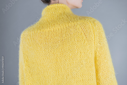 Close up back of yang woman in yellow sweater. People concept. Grey background