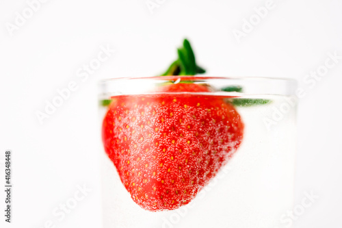 Strawberries in grall of water on white background. Advertising cocktails. Juicy fruits under water. Being shot as they submerged under water. A healthy form of product promotion. photo