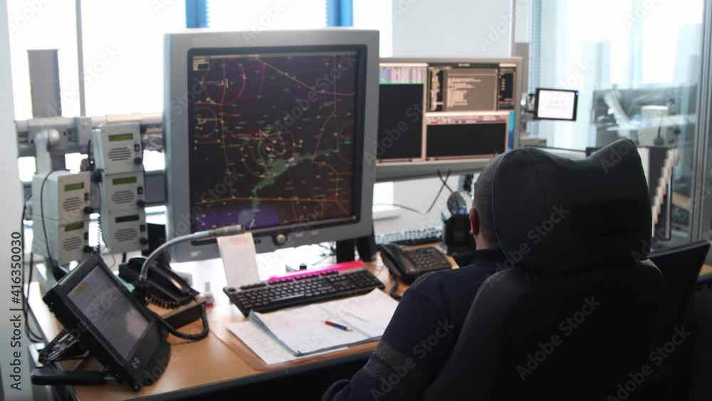 Navigation control room in the airport - a man working with a monitor with fly paths placed on the map Navigation control room in the airport - a man working with a monitor with fly paths placed on the map