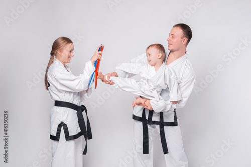 Young family with their little boy practicing martial arts over white background.