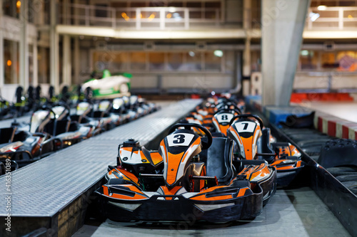 Kart cars parked one by one on indoor go-kart racing track in anticipation of drivers. Shallow focus. © mark_ka