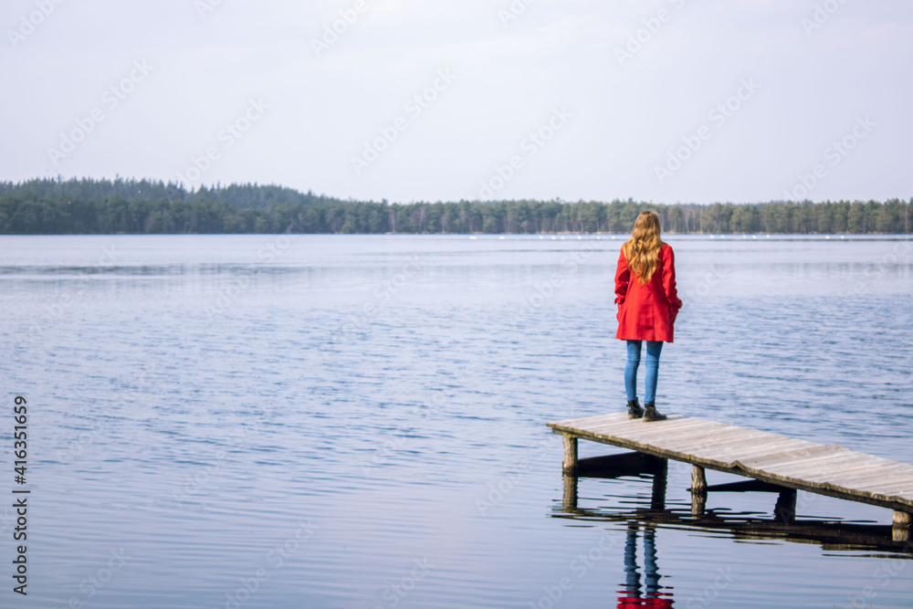 Girl in a red coat by the lake