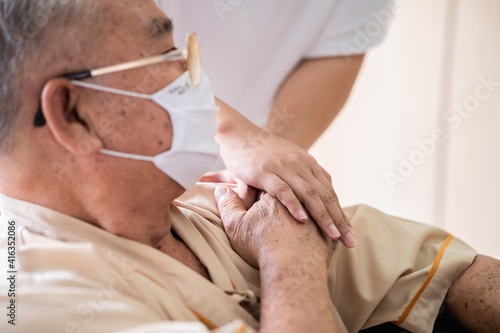 Close up hands of medical doctor or cousin family carefully holding senior patient's hands wearing face mask for prevent virus infection in comfort and console during recovery in hospital. 