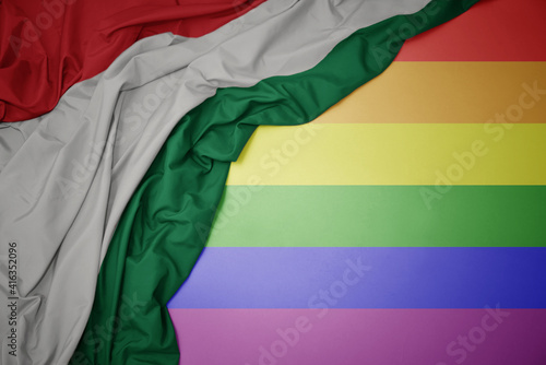 waving national flag of hungary on a gay rainbow flag background.