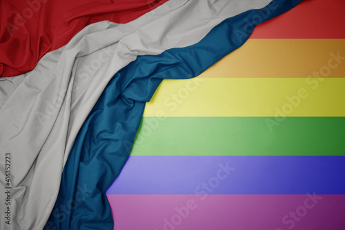 waving national flag of luxembourg on a gay rainbow flag background.