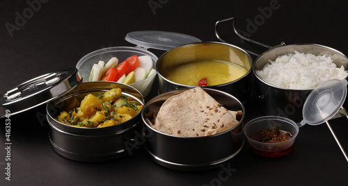 Typical Stainless steel Lunch Box or Tiffin with Maharashtrian food menu Chapati OR Roti, Plain Dal Tadka, White Rice Potato sabji with salad and pickle