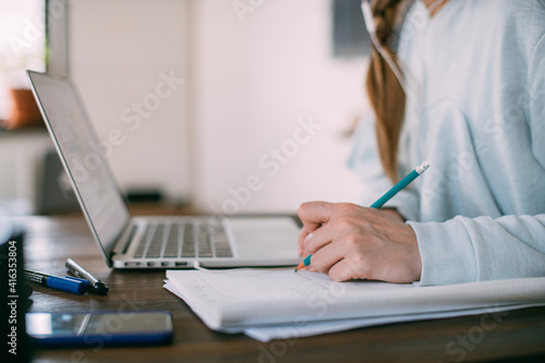 Woman works at a laptop at home. Hand with a pencil close-up