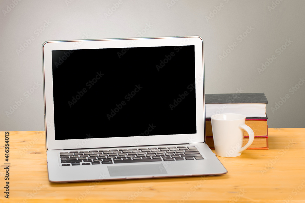Laptop with blank screen, cup of coffee and books or notebooks on a wooden table. mockup for your text Laptop with blank screen, cup of coffee and books or notebooks on a wooden table. mockup for your text