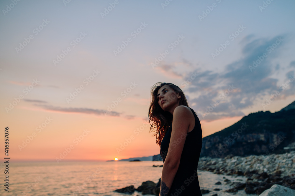 Pretty brunette girl looking at sunset on sea 