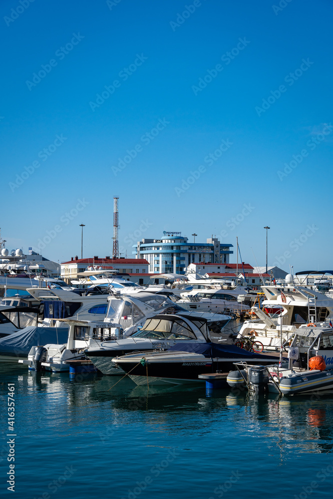 Yachts and boats at pier of Sochi Commercial Sea Port. In background is new Rosmorport building. Center of resort town. Clear sunny winter day. Sochi, Russia - 07 December 2020 Yachts and boats at pier of Sochi Commercial Sea Port. In background is new Rosmorport building. Center of resort town. Clear sunny winter day. Sochi, Russia - 07 December 2020