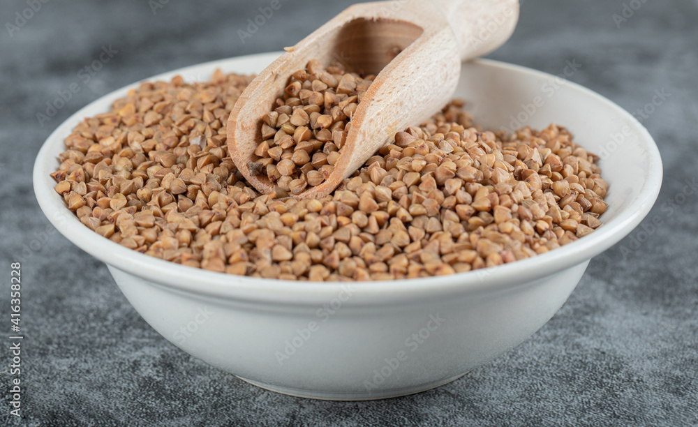 Bowl of raw buckwheat on marble background Bowl of raw buckwheat on marble background