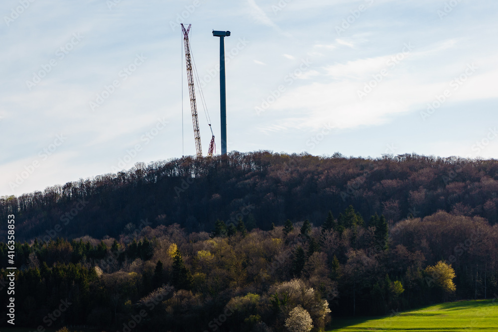 Country landscape with crane at wind turbine