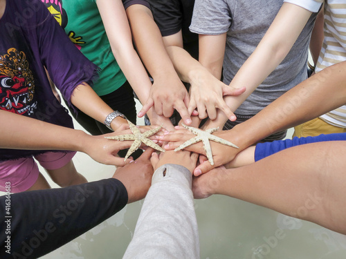 Close up top view of young business people standing on beach putting their hands together. Stack of hands. Unity and teamwork concept.