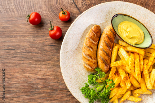 German fried sausages with French fries and mustard sauce. View from above