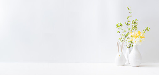 Home interior with easter decor. Daffodils in a vase, spring flowers on a light background