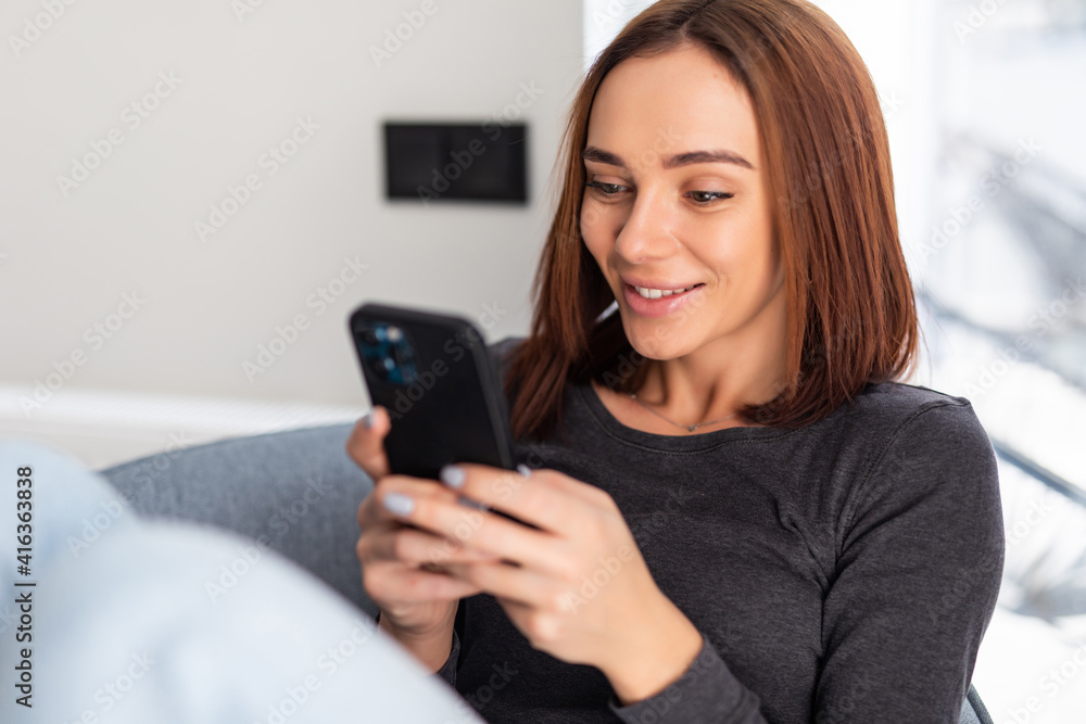Young woman sit armchair use smartphone wear casual style clothes in house indoors Young woman sit armchair use smartphone wear casual style clothes in house indoors