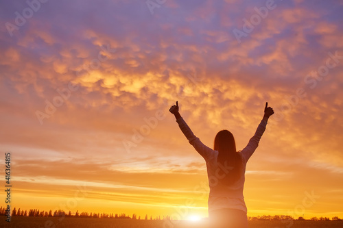 woman feeling victorious facing the beautiful sunset.
