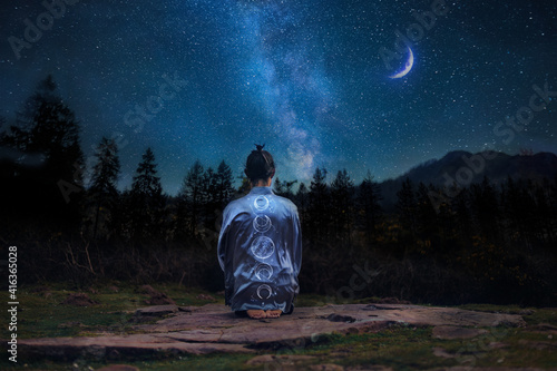 Young man in meditating on the mountain under a starry sky photo