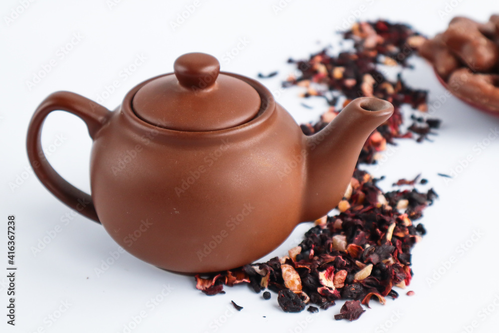 Fruit tea in a ceramic teapot and sprinkled hibiscus tea leaves
