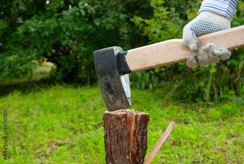 Wood chopping at backyard. Man's hand holding axe preparing to chop a log. Outdoors. Copyspace. Summer.