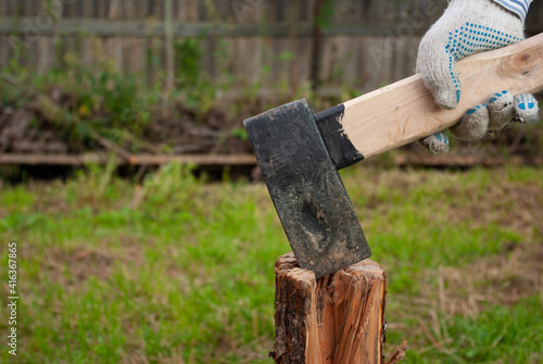 Wood chopping at backyard. Man's hand holding axe preparing to chop a log. Outdoors. Copyspace. Summer.