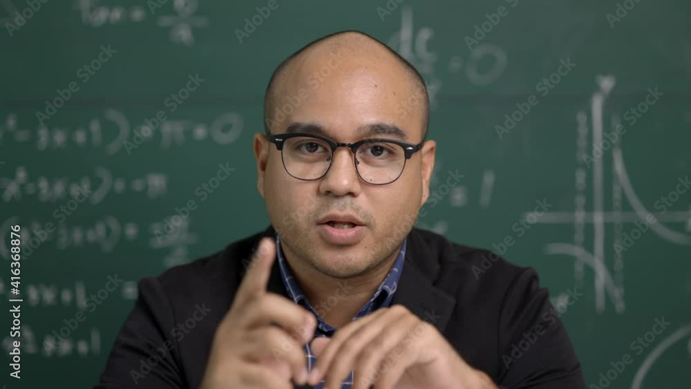 Indian young teacher man looking at camera sitting teaching online video conference live stream. Asian teacher teaching class webinar online for students learning. Indian young teacher man looking at camera sitting teaching online video conference live stream. Asian teacher teaching class webinar online for students learning.