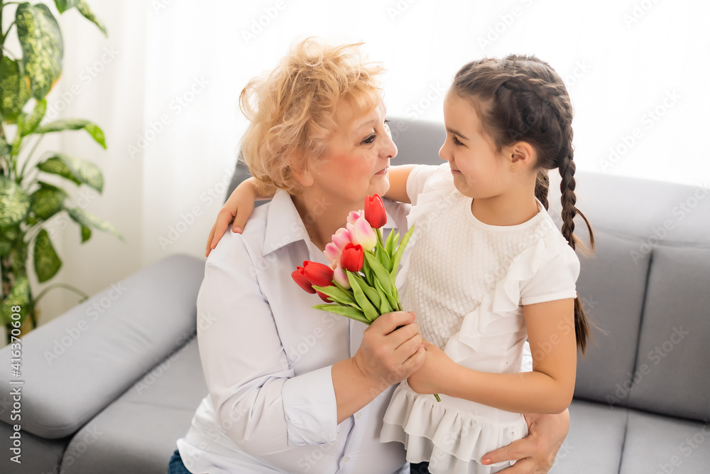 Nice little girl presenting bouquet to her grandmother in light room Nice little girl presenting bouquet to her grandmother in light room