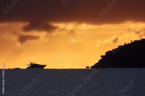 Silhouette einer Motoryacht kreuzt am Horizont im orangefarbenen Morgenlicht