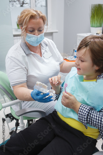 Vertical shot of a professional dentist talking to her young patient after dental examination