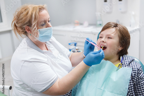 Professional dentist giving fluoride dental treatment to a young boy photo