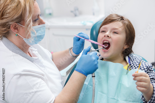 Professional dentist giving fluoride dental treatment to a young boy
