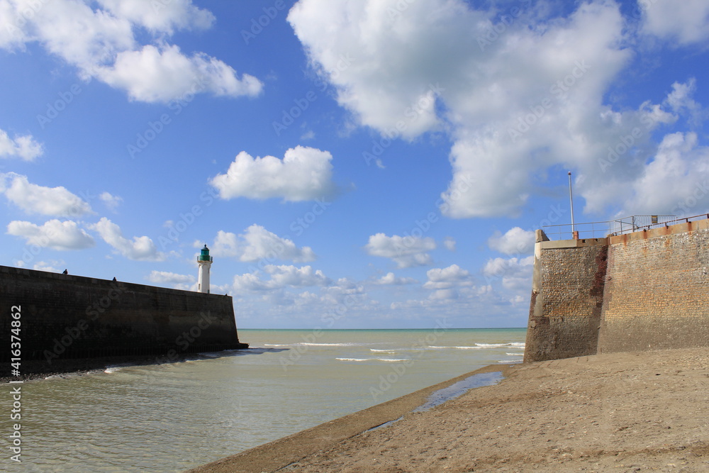 a beautiful seascape with the entrance of the harbour with two piers with lighthouses in saint valery en caux at the french coast in normandy and a blue sky with clouds in summer