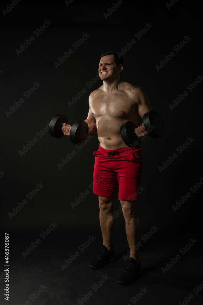 Fitness man presses dumbbells in red panties business caucasian man, torso isolated fitness. Happiness content, success elegance background black bodybuilder
