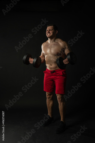 Fitness man presses dumbbells in red panties business caucasian man, torso isolated fitness. Happiness content, success elegance background black bodybuilder © Ilya