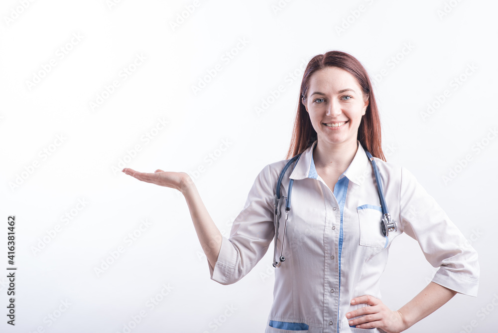 Portrait of a female doctor in a white uniform that shows a palm with copyspace in the studio on a white background Portrait of a female doctor in a white uniform that shows a palm with copyspace in the studio on a white background