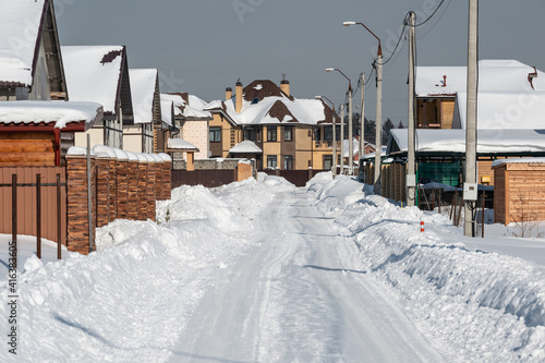 Snowy road with big snowdrifts among cottage houses