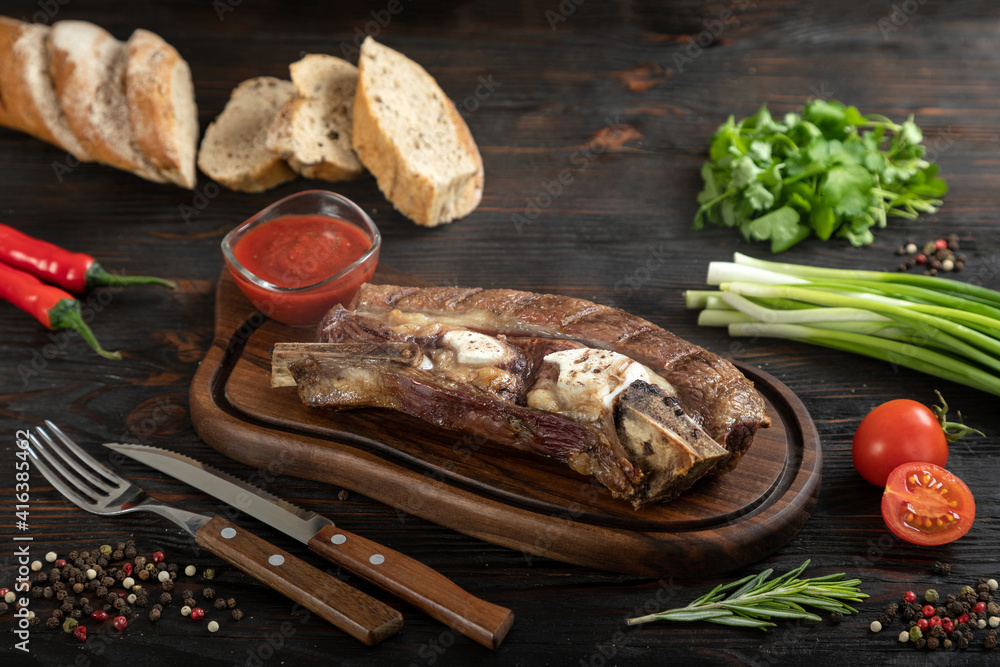 Roasted beef on the bone on a board for serving.