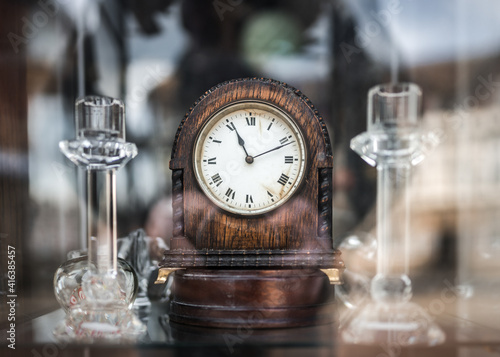 Foto Old wooden mechanical wind up clock standing in antique shop window with reflections shining on glass telling time eleventh minute to passers by