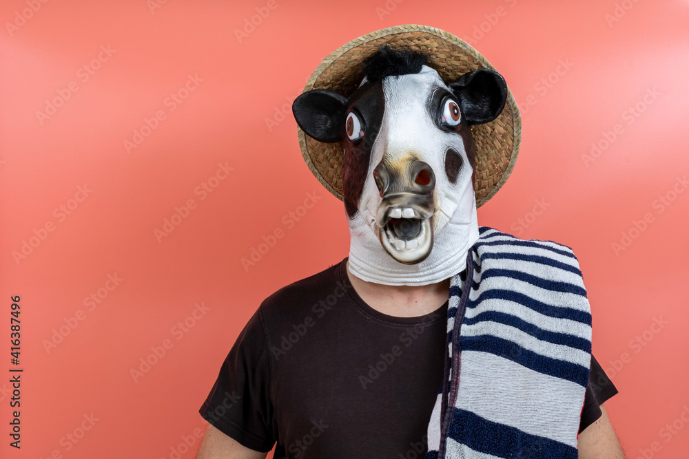 person in cow's head costume with towel and straw hat ready to go to the beach or swimming pool person in cow's head costume with towel and straw hat ready to go to the beach or swimming pool