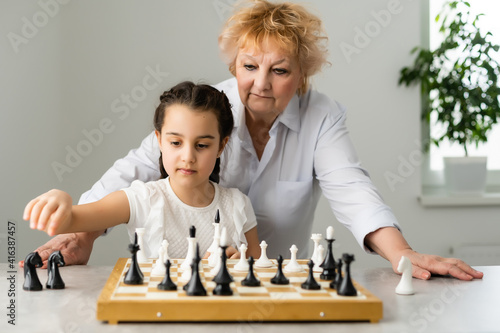 Grandmother and young girl playing chess together at home