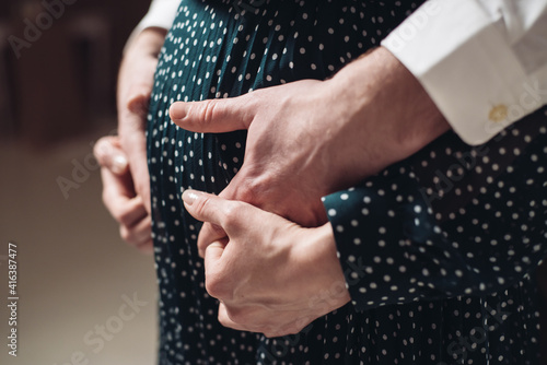 A pregnant woman holds her husband's hands on her belly
