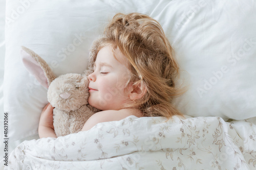 Close-up of a little girl sleeping and hugging her plush rabbit. Relaxation. Healthy sleep. © Kristina89