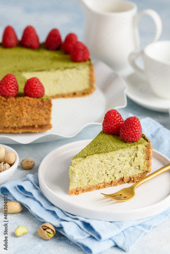 Cheesecake with pistachios and matcha tea decorated with fresh raspberries. Piece of cheesecake on plates Cheesecake with pistachios and matcha tea decorated with fresh raspberries. Piece of cheesecake on plates