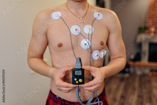 Heart electrocardiogram or monitoring using Holter for young patient. Male athlete does a cardiac stress test. wearing Holter monitor device for daily monitoring of an electrocardiogram.  photo